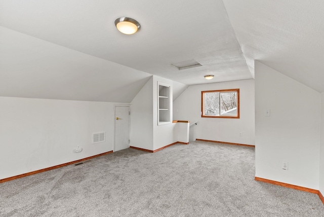 additional living space with vaulted ceiling, carpet, and a textured ceiling