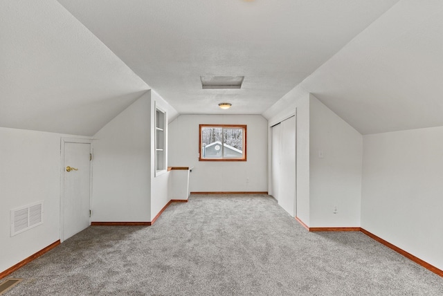 additional living space with lofted ceiling, carpet floors, and a textured ceiling