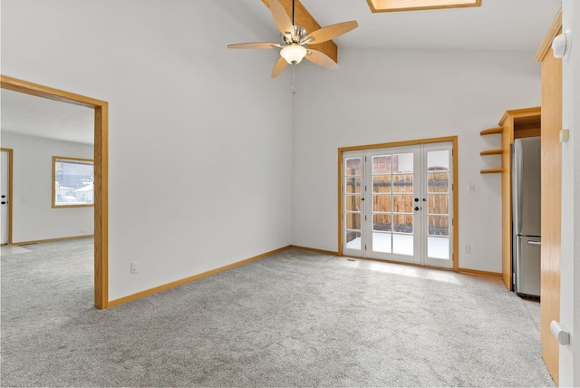 carpeted spare room featuring high vaulted ceiling, french doors, and ceiling fan