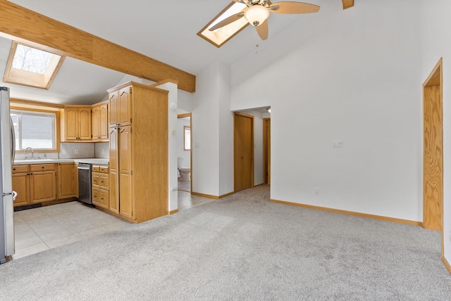 kitchen with refrigerator, a skylight, beamed ceiling, dishwasher, and light carpet