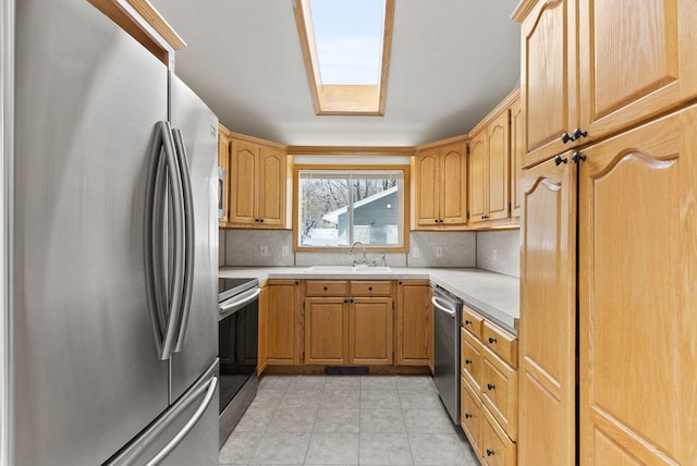 kitchen with light tile patterned floors, appliances with stainless steel finishes, sink, and backsplash