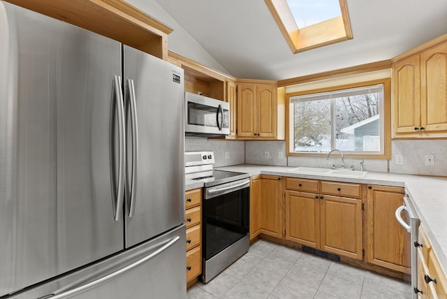 kitchen with vaulted ceiling with skylight, sink, backsplash, light tile patterned floors, and stainless steel appliances