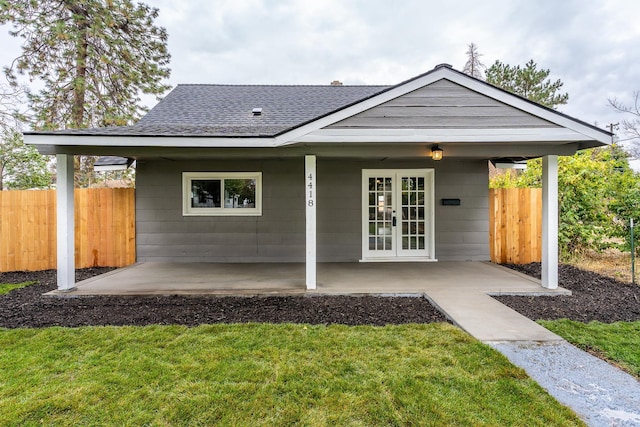 rear view of house featuring a patio, a lawn, and french doors