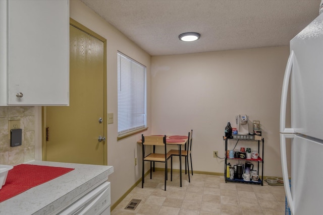 kitchen with white cabinets, white fridge, and a textured ceiling