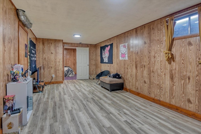 unfurnished room with light hardwood / wood-style flooring and wood walls