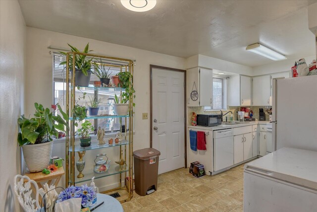 kitchen featuring white cabinetry, backsplash, and white appliances