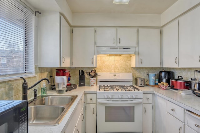 kitchen with decorative backsplash, sink, gas range gas stove, and white cabinets