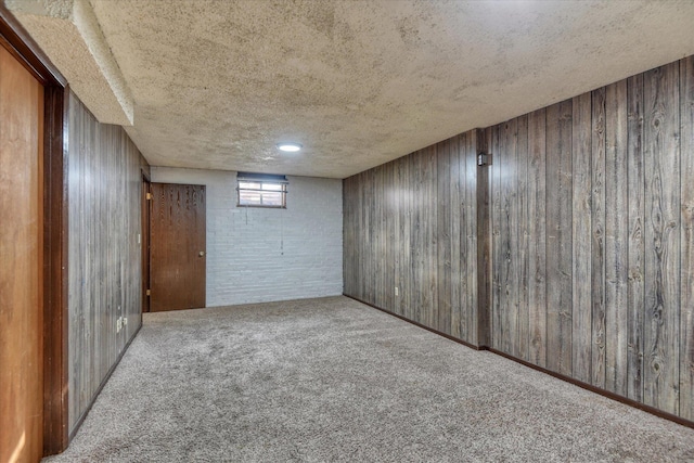 basement featuring carpet floors, a textured ceiling, and wood walls