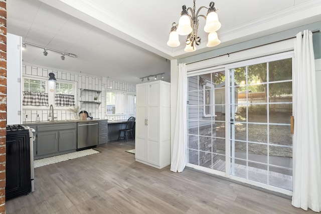 unfurnished dining area with a sink, track lighting, a notable chandelier, and wood finished floors