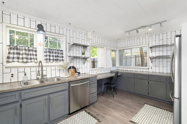 kitchen with stainless steel appliances, sink, built in desk, and gray cabinets