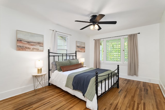 bedroom with wood finished floors, baseboards, ceiling fan, and multiple windows