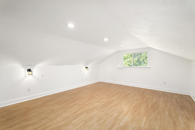 additional living space featuring light wood-type flooring, baseboards, lofted ceiling, and recessed lighting