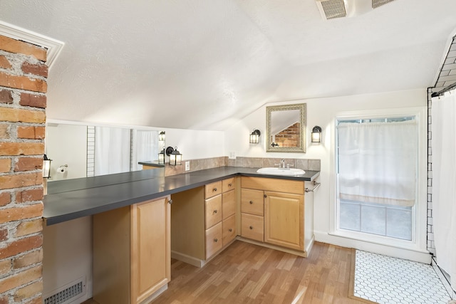 bathroom featuring hardwood / wood-style flooring, vanity, lofted ceiling, and a textured ceiling