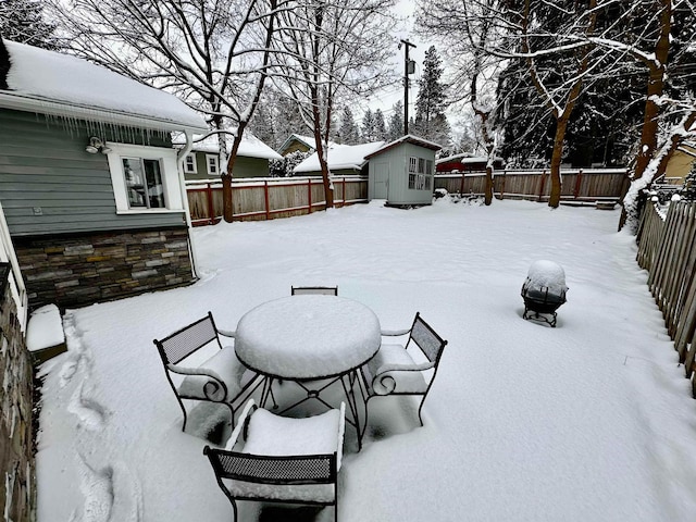 snow covered patio with a storage shed