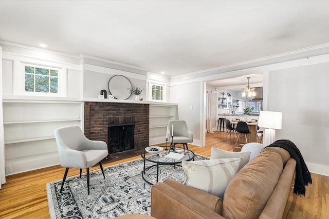 living room featuring a brick fireplace, wood-type flooring, ornamental molding, and a chandelier