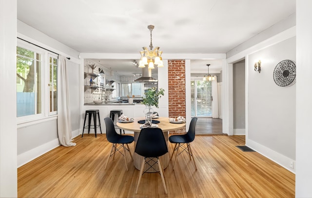 dining area featuring a notable chandelier, light wood-type flooring, baseboards, and visible vents