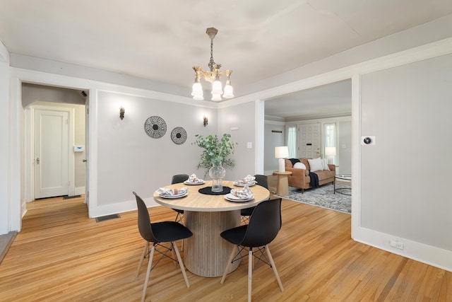 dining area featuring light hardwood / wood-style floors and a notable chandelier