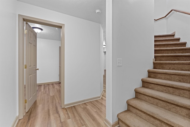 stairs featuring wood-type flooring and a textured ceiling