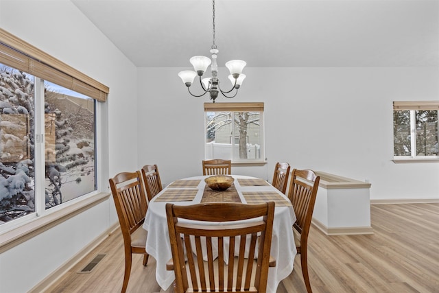 dining space with a notable chandelier, light hardwood / wood-style flooring, and a wealth of natural light