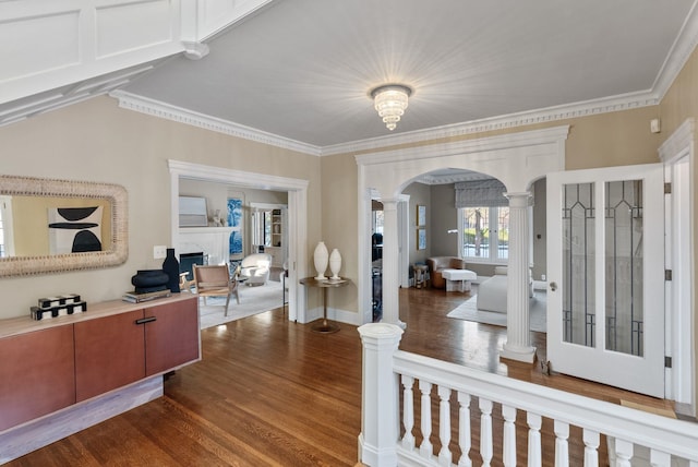 entrance foyer featuring crown molding, a high end fireplace, wood-type flooring, and decorative columns