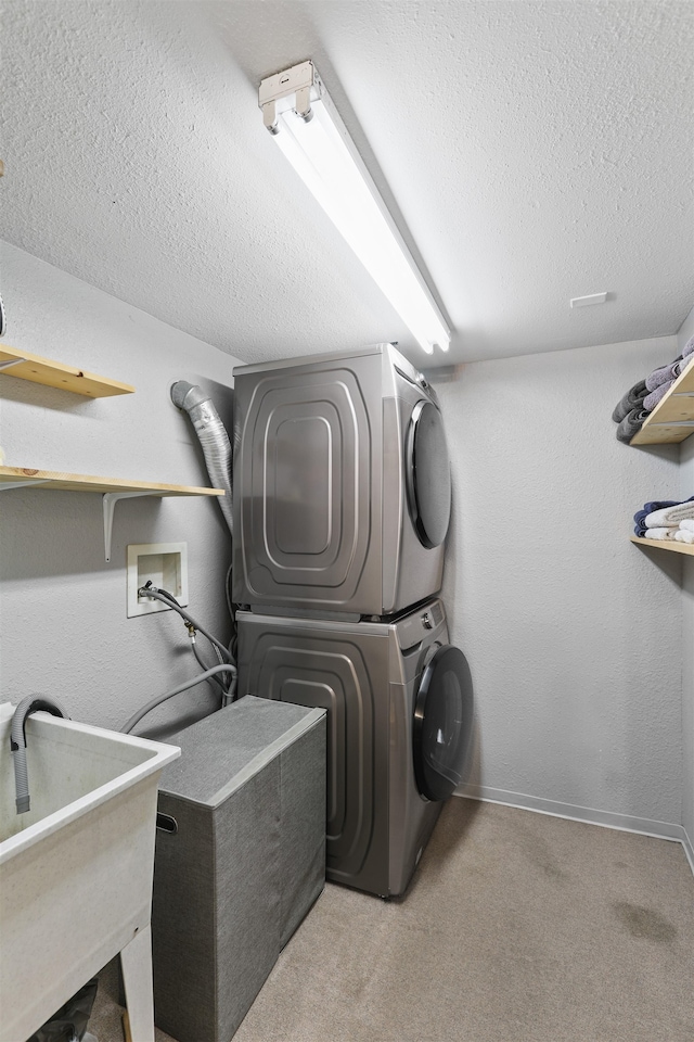 laundry area with light colored carpet, stacked washer and clothes dryer, sink, and a textured ceiling