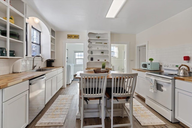 kitchen featuring sink, white appliances, butcher block counters, white cabinetry, and washing machine and clothes dryer