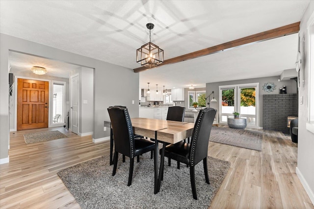 dining space featuring a fireplace, light hardwood / wood-style flooring, and a chandelier