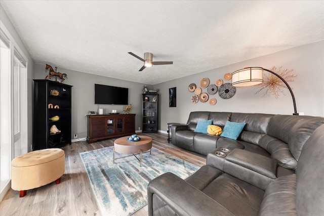 living room with wood-type flooring, ceiling fan, and a textured ceiling