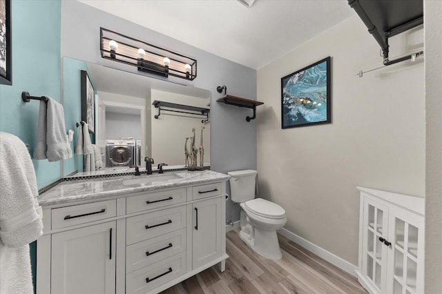 bathroom with vanity, wood-type flooring, independent washer and dryer, and toilet