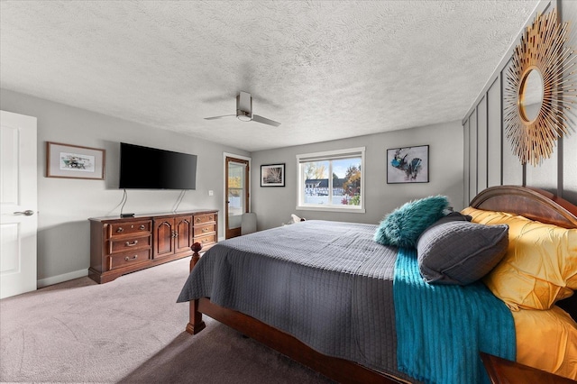 carpeted bedroom featuring ceiling fan and a textured ceiling