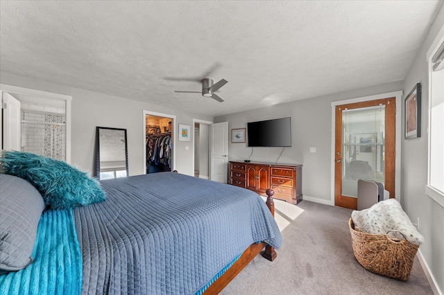 carpeted bedroom featuring a spacious closet, a textured ceiling, ceiling fan, and a closet