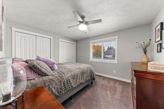 carpeted bedroom featuring two closets, a textured ceiling, and ceiling fan