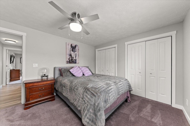 bedroom featuring ceiling fan, a textured ceiling, carpet, and two closets