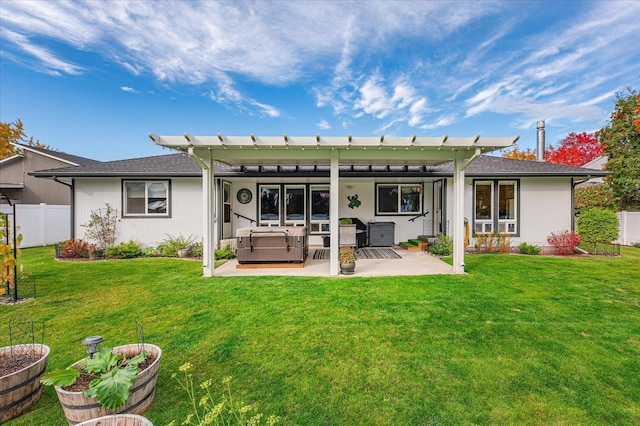 back of house featuring a lawn, a hot tub, and a patio area