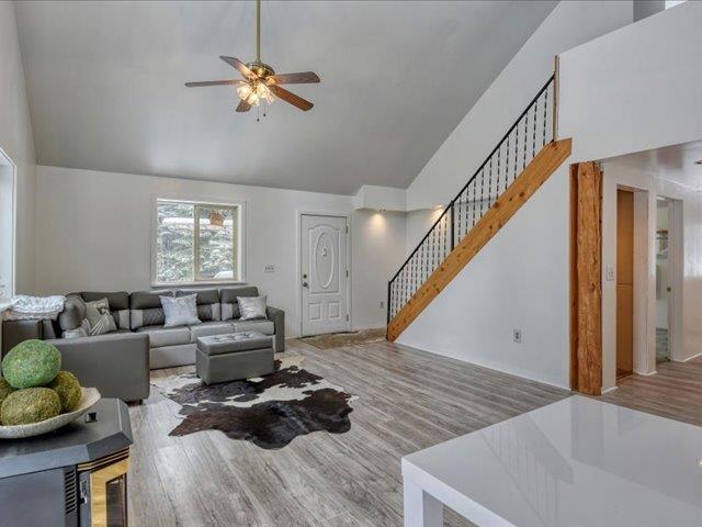 living room featuring ceiling fan, plenty of natural light, light wood-type flooring, and high vaulted ceiling