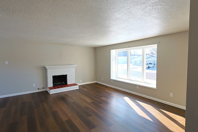 unfurnished living room with a brick fireplace, dark wood-type flooring, and a textured ceiling