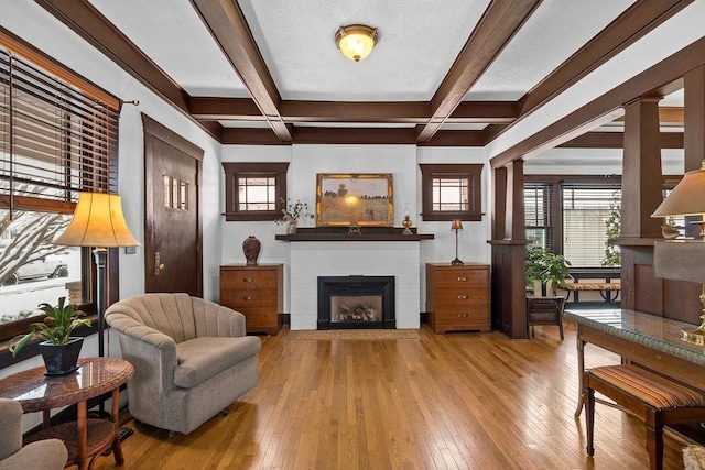 living room with coffered ceiling, beam ceiling, light hardwood / wood-style flooring, and ornate columns