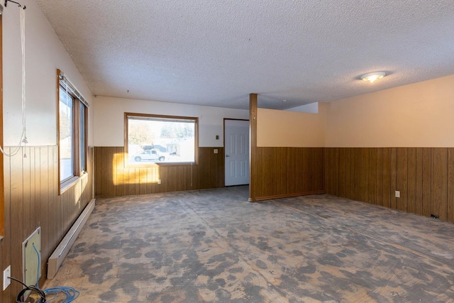 unfurnished room featuring dark carpet, wood walls, a textured ceiling, and baseboard heating