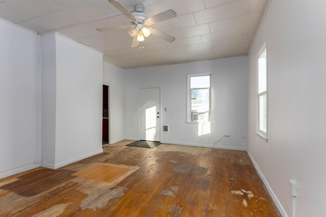 empty room featuring ceiling fan, a healthy amount of sunlight, and hardwood / wood-style floors