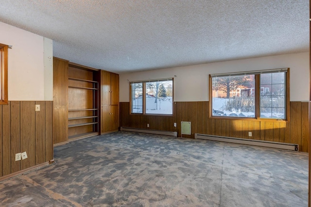 interior space with a baseboard radiator, a textured ceiling, and wooden walls