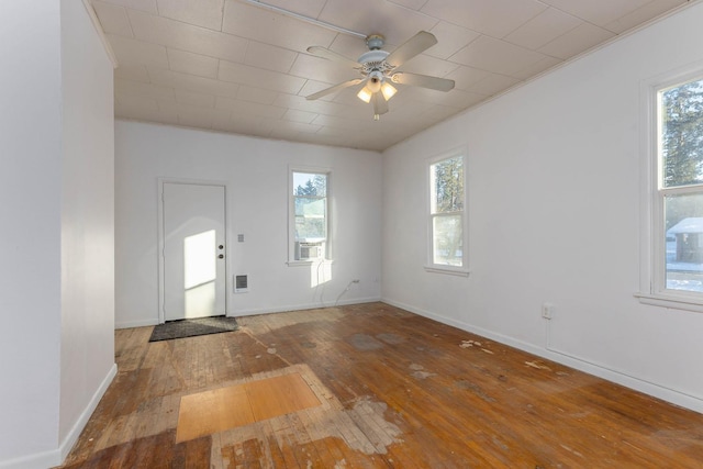 empty room with ceiling fan, wood-type flooring, and a wealth of natural light