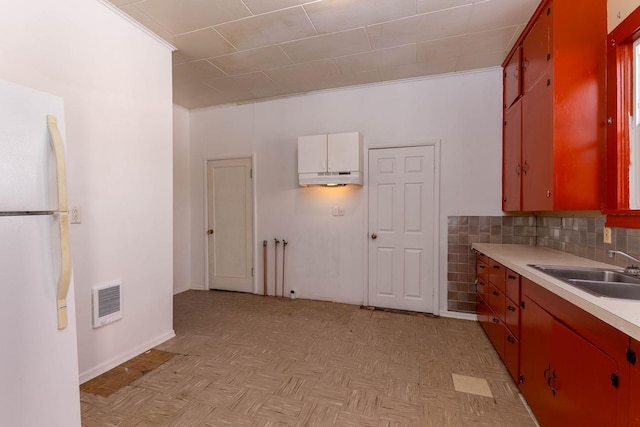 kitchen with tasteful backsplash, sink, white fridge, and light parquet floors