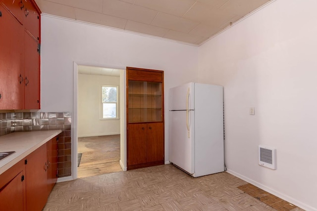 kitchen with white refrigerator, light parquet flooring, and tasteful backsplash