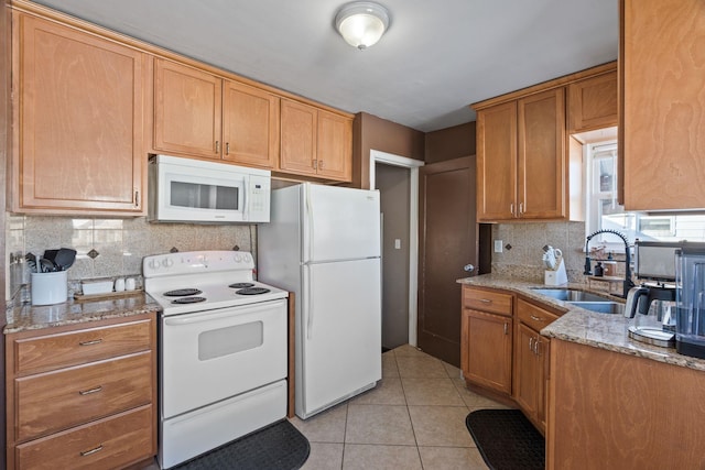 kitchen with tasteful backsplash, sink, light tile patterned floors, light stone counters, and white appliances