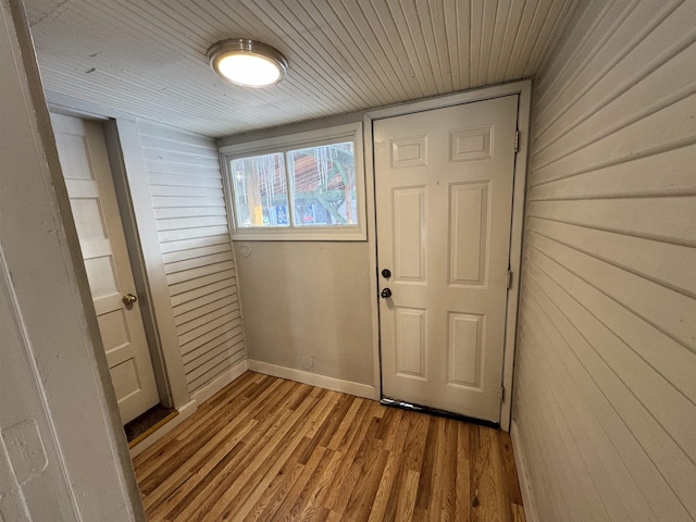 doorway featuring wood ceiling, light hardwood / wood-style flooring, and wood walls