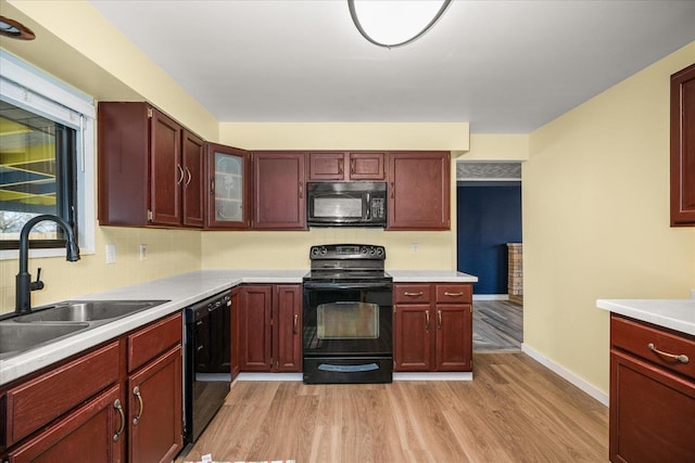 kitchen featuring light wood-type flooring, sink, decorative backsplash, and black appliances