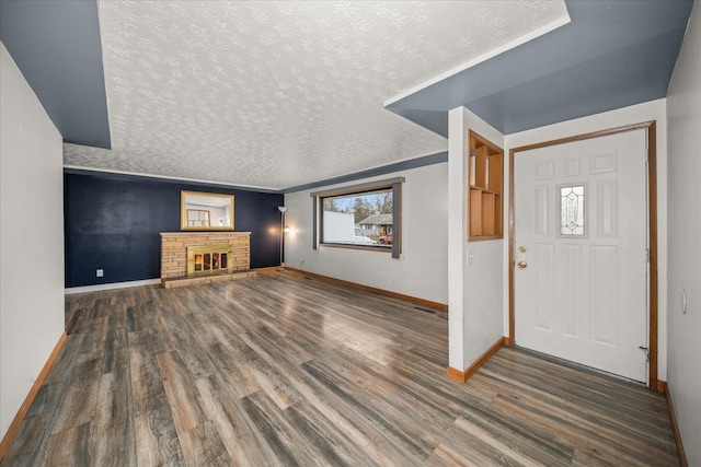 entryway featuring dark hardwood / wood-style floors, a stone fireplace, and a textured ceiling