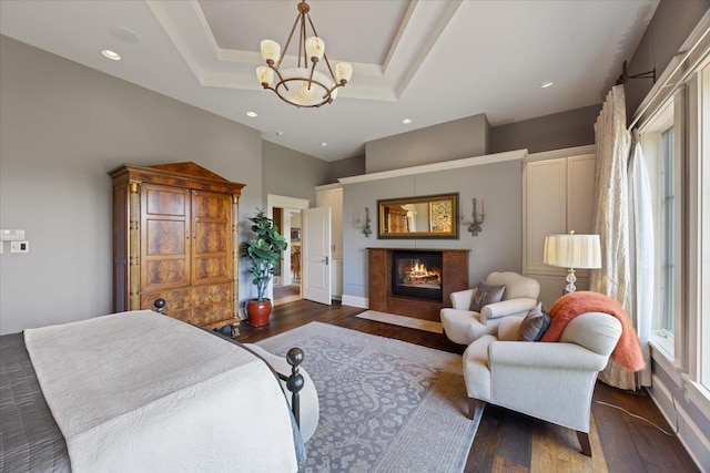 bedroom featuring an inviting chandelier, a tray ceiling, dark hardwood / wood-style floors, and a high ceiling