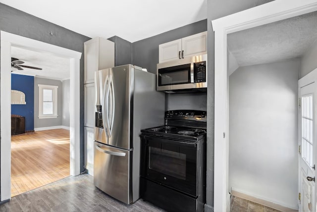 kitchen featuring white cabinetry, a textured ceiling, hardwood / wood-style flooring, ceiling fan, and stainless steel appliances