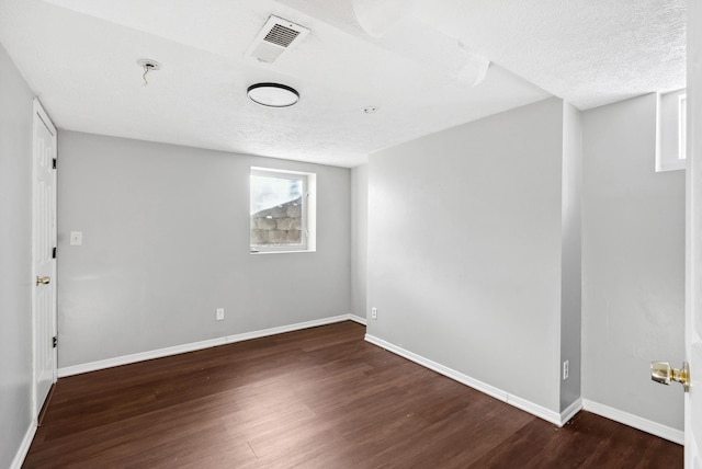 unfurnished room featuring dark hardwood / wood-style flooring and a textured ceiling